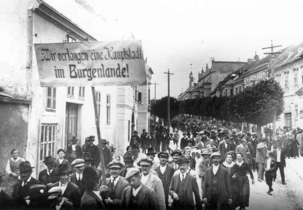 Historische schwarz-weiß-Aufnahme von 1925 von großer Menschengruppe, die durch eine Straße zieht